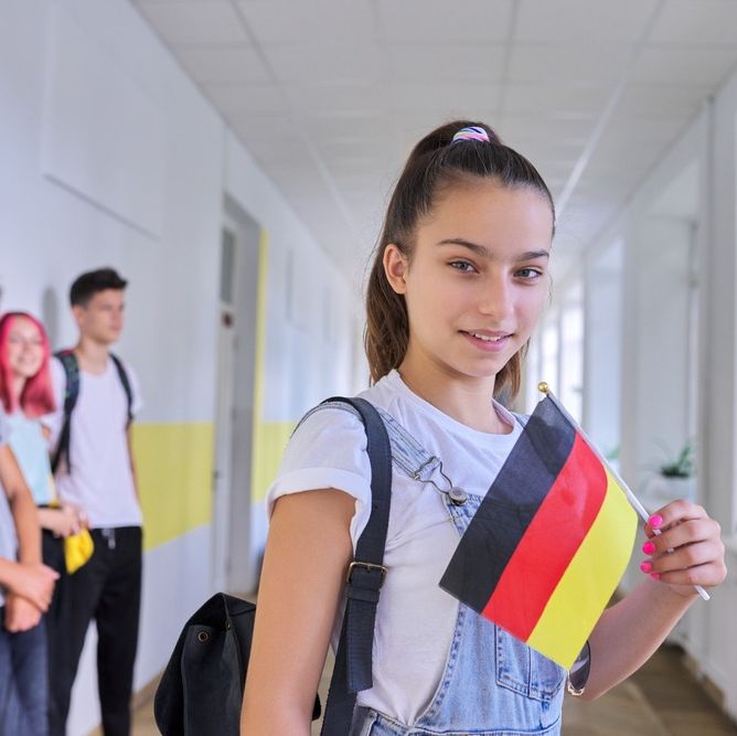 chica joven en pasillo de colegio con bandera de alemania